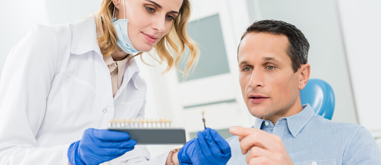 Dentist and patient choosing tooth implants in modern dental clinic