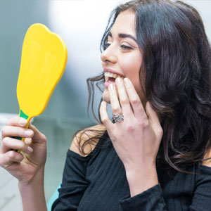 Lady checking new dental implants in mirror