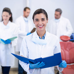 Smiling dentist holding file at dental clinic