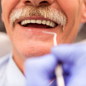 Elderly man getting examined at dental office