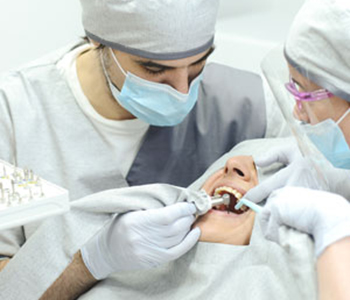 Dentist surgeon performing emergency dental surgery with assistant