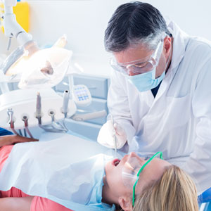Dentist examining a patients teeth in the dentists chair at the dental clinic