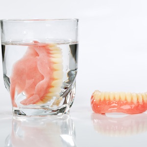 A set of dentures in a glass of water