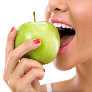 Woman biting a green apple isolated on white background