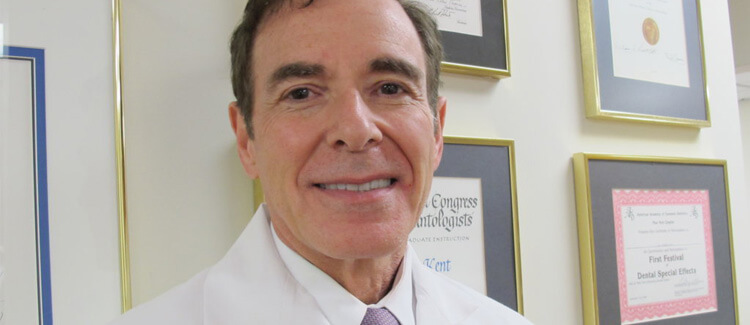 Dr. Gordon Kent standing in front of award wall